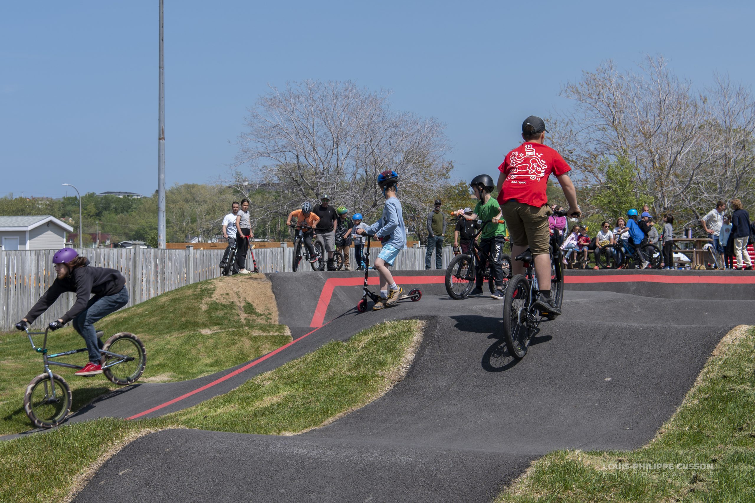 Un grand groupe de jeunes s’amusant sur le Pumptrack de Matane lors de son inauguration.