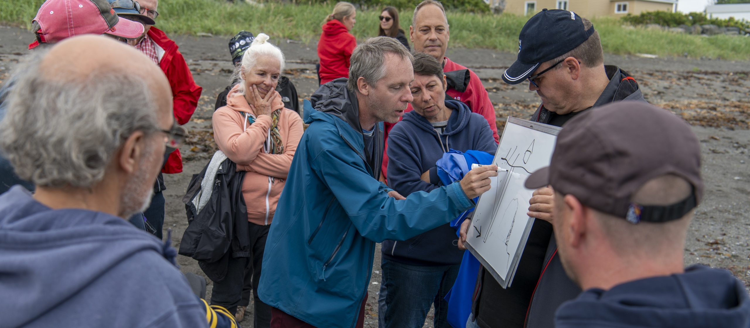 Séance de consultation publique sur le bord de mer à Matane où les citoyens dessinent leurs idées sur un tableau blanc portatif